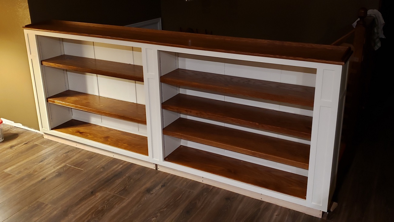 White and stained oak built in bookshelf in front of stairs night