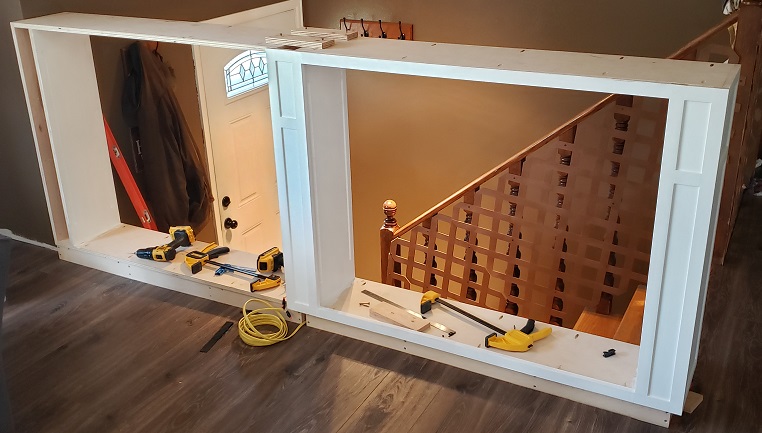 White shaker style built in bookshelf partially installed in front of stairs