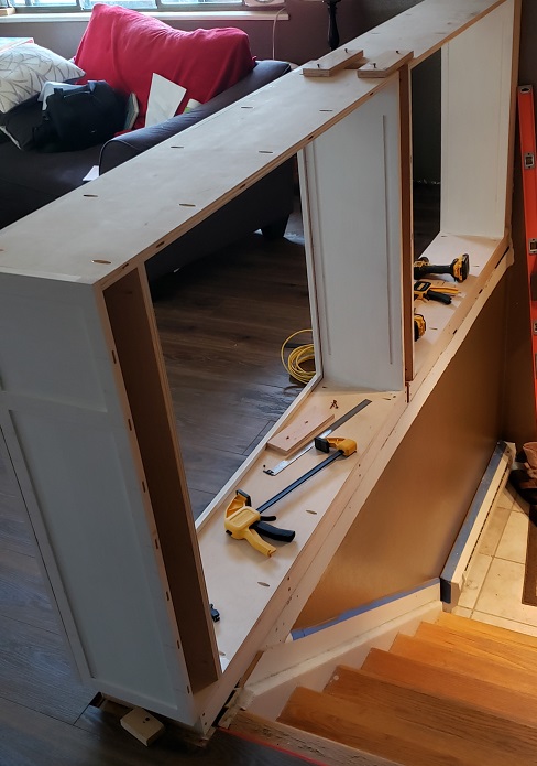 White shaker style built in bookshelf partially installed behind stairs