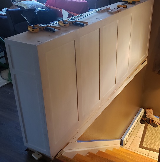 White shaker style built in bookshelf partially installed behind stairs