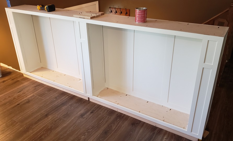 White shaker style built in bookshelf body and panels installed in front of stairs