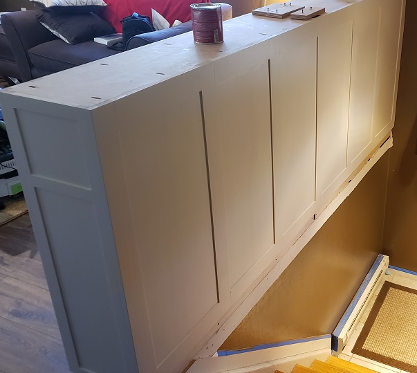 White shaker style built in bookshelf body and panels installed behind stairs