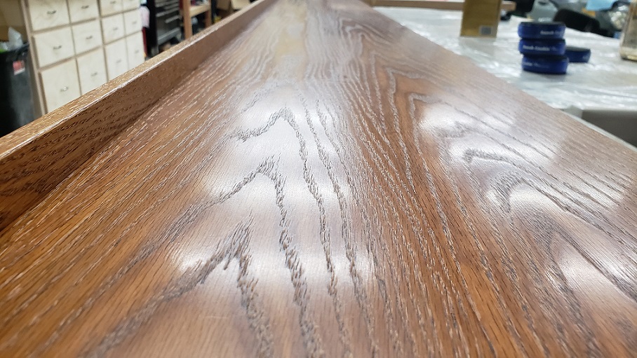 Close view of long oak bookshelf top with Minwax wipe on polyurethane applied