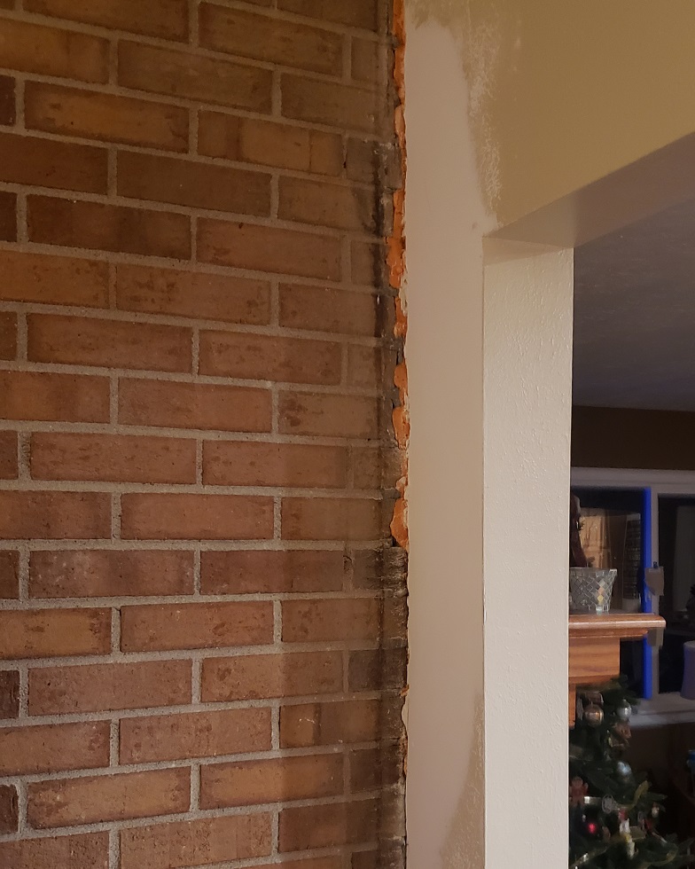 Patch drywall wall next to exposed brick