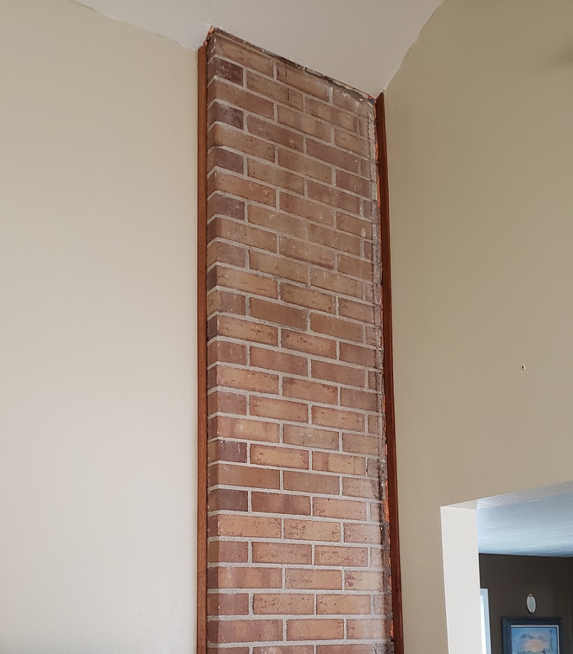 Exposed chimney side with oak trim on tan wall