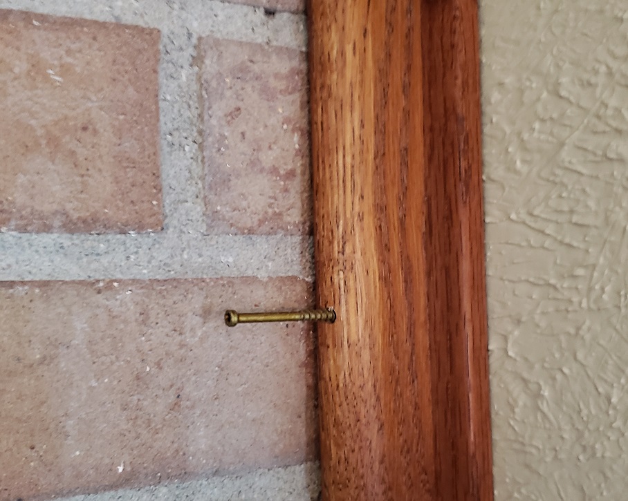 Trim head screw attaching oak trim to wall next to exposed brick