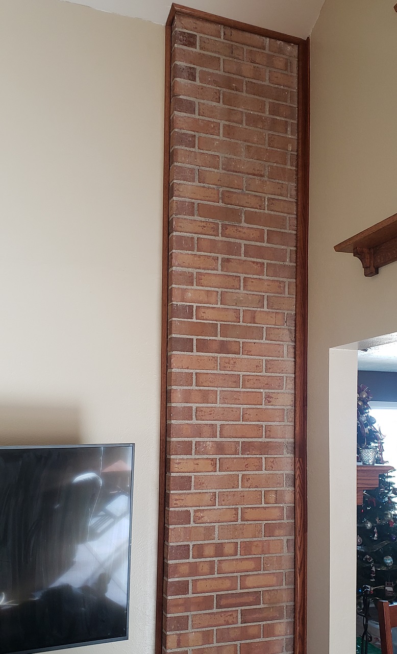 Exposed chimney side with oak trim on tan wall