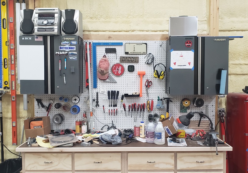Woodworking workbench with metal cabinets and tools on pegboard