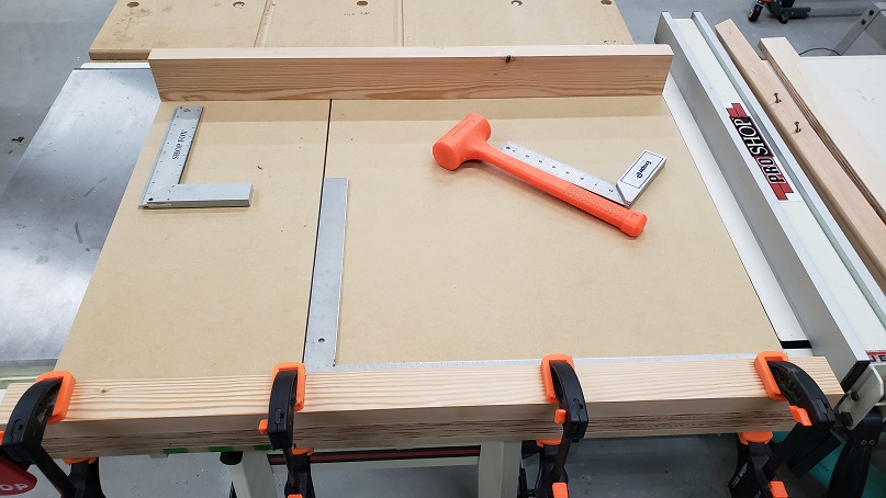 Attaching a rear fence to a tablesaw crosscut sled with Task clamps, squares, and an orange mallet