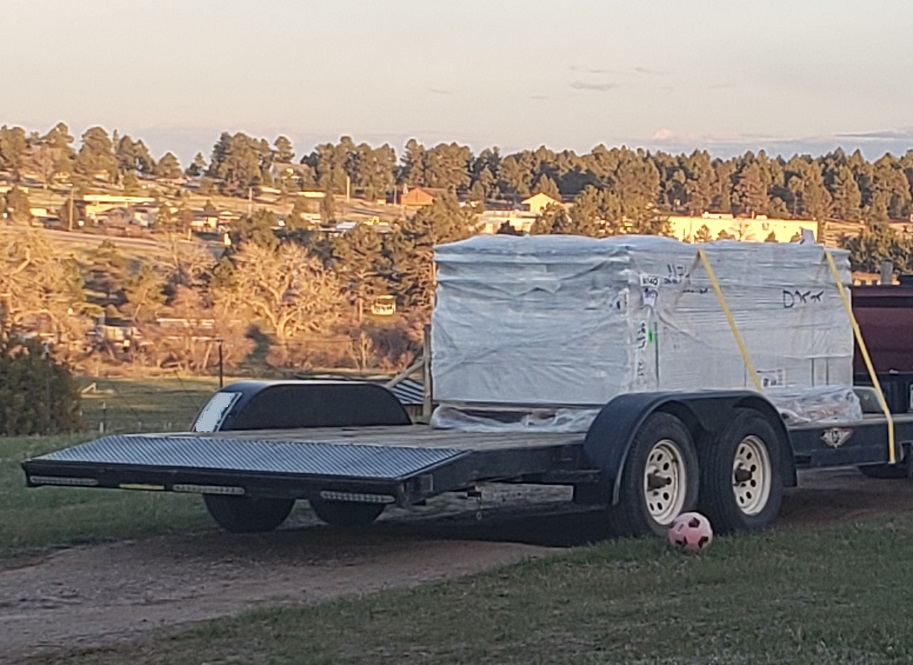 Heartland shed kit on black flatbed trailer with dovertail