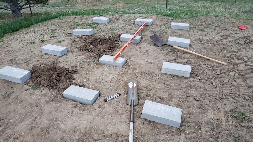 Cinder block caps being dug into the ground with level and shovels