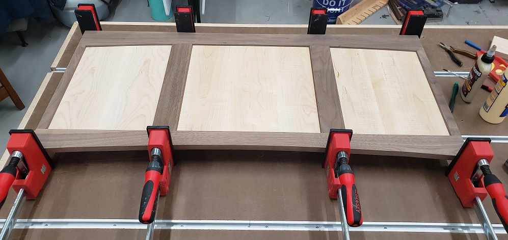 Glue up of walnut and maple shaker style panel with Bessey Revo clamps on workbench