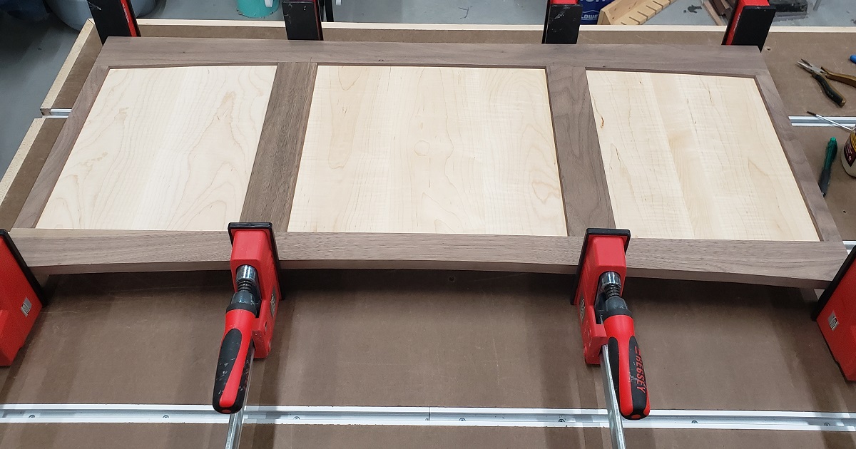 Clamping of a walnut and maple modified shaker panel for a hope chest with Bessey Revo clamps