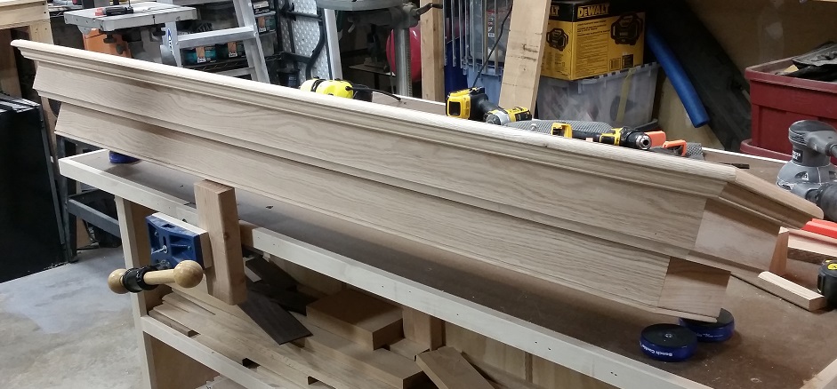 Unfinished oak fireplace mantel sitting on workbench