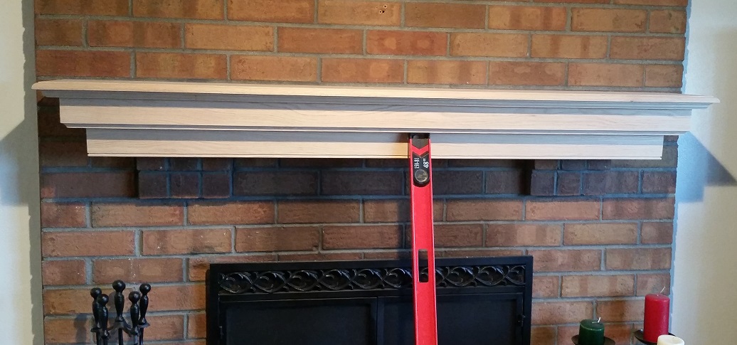 Unfinished oak fireplace mantel temporarily held in place with level for mock up