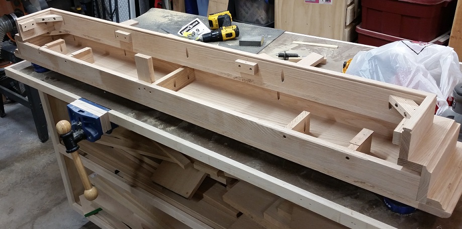 Back side of oak fireplace mantel on workbench with Rockler vise