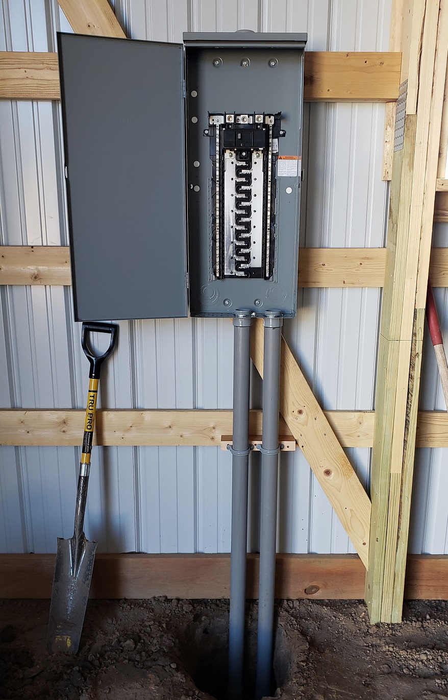 Square D outdoor electrical panel on pole barn wall with PVC conduit running to floor