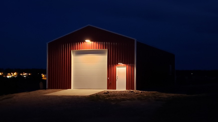 Red and white pole barn with down lights over doors