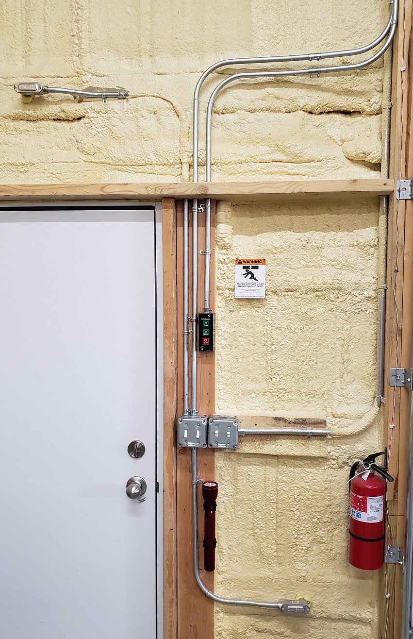 EMT conduit switches and door controller installed in pole barn next to white door