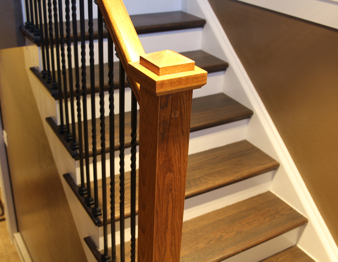 Craftsman style oak newel post in front of dark stair treads and white risers