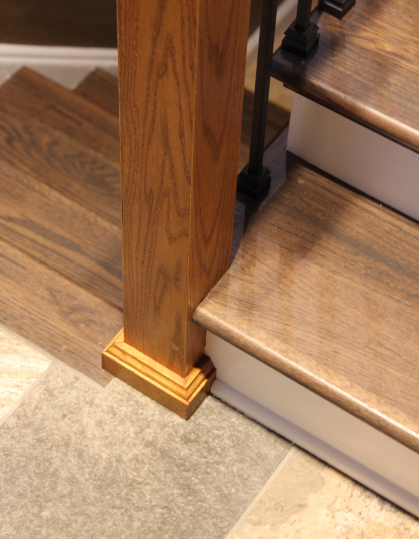 Newel post cleanly attached to stair stringer with white and oak trim