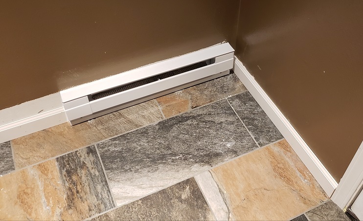 Stone look porcelain tile on stair landing with white trim and brown wall