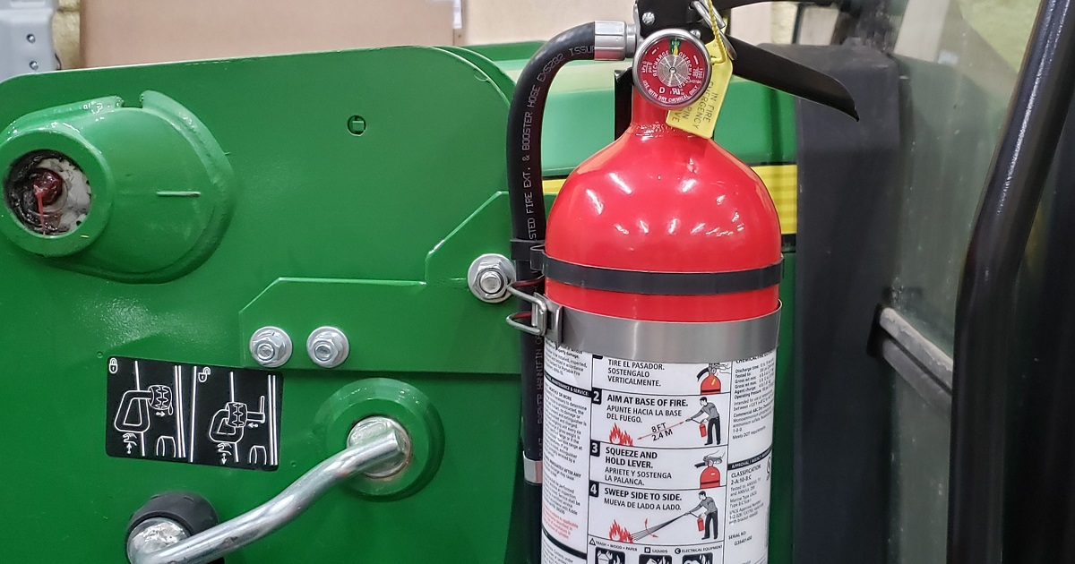 Fire extinguisher mounted to a John Deere 520M loader on a 5055E tractor
